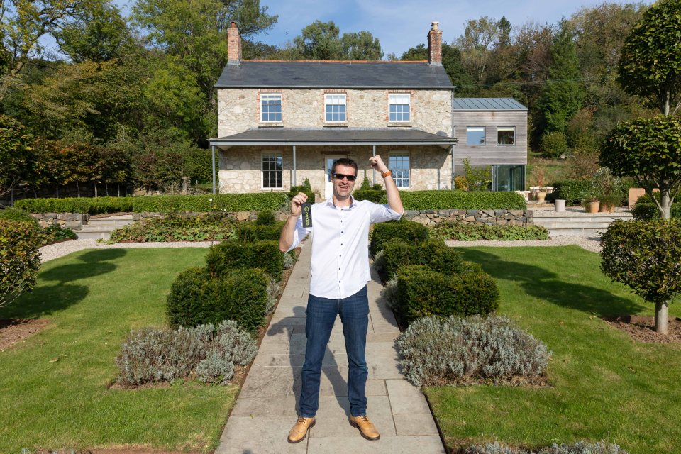 Omaze Million Pound House draw winner Simon Williams celebrating outside his new £2.2m home in Devon