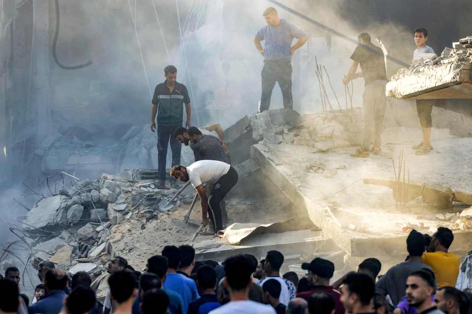 People dig and search through the rubble of a destroyed building in southern Gaza