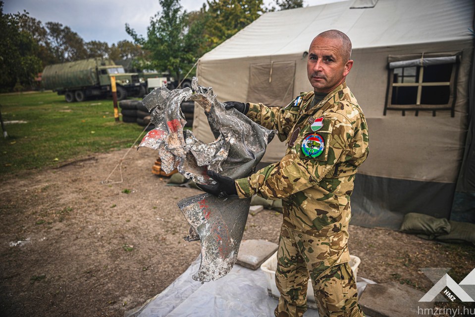 A Hungarian soldier holds up a mashed up part of the fighter