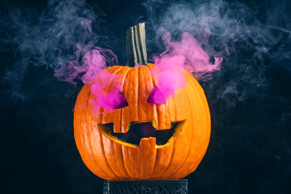 A jack o' lantern with purple smoke coming out of it's eyes.