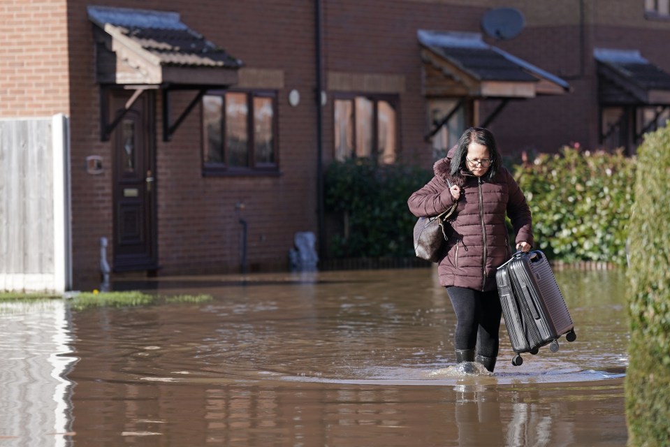 A resident with a suitcase walks through flood water in Retford in Nottinghamshire