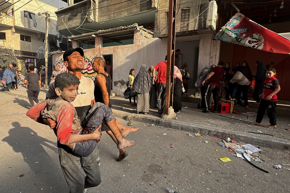 A man carries a wounded child in the aftermath of the airstrike