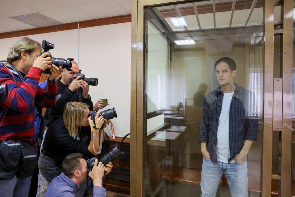 Reporters take pictures of Evan inside his glass cage at a court hearing