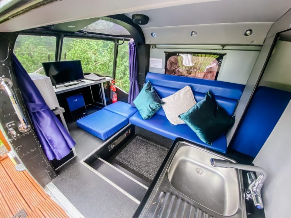 The interior of the helicopter home includes a sofa bed, sink area and desk