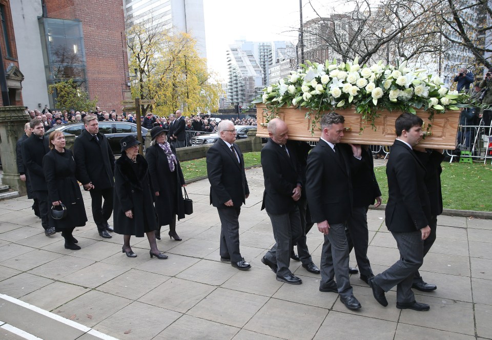 Pallbearers carry the coffin of Sir Bobby as widow, Norma Charlton walks behind