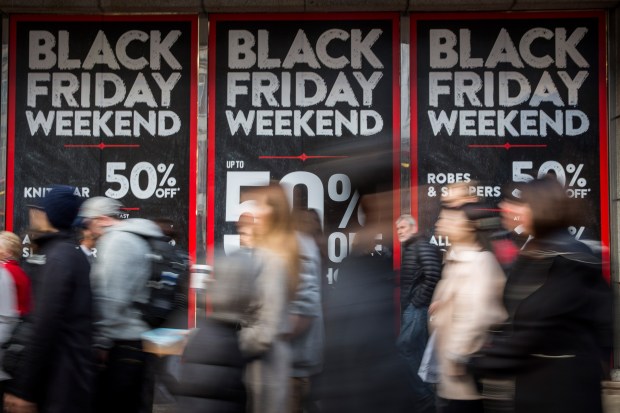 a group of people walking in front of black friday weekend signs