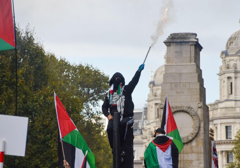 A pro-Palestine protester sets off fireworks near The Cenotaph in London at an earlier march