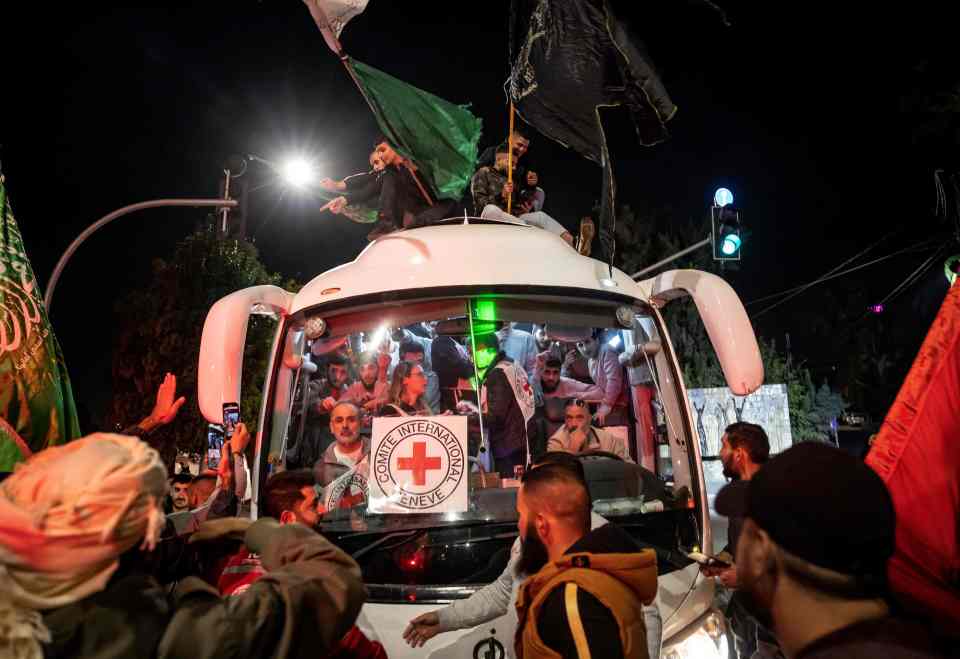 A crowd surrounds a Red Cross bus carrying Palestinian prisoners released from Israeli jails in exchange for hostages released by Hamas from the Gaza Strip