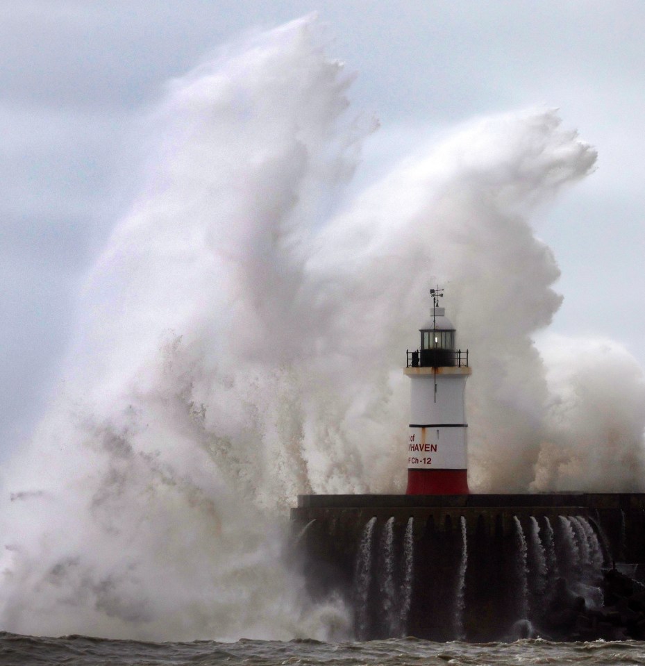 Waves crash against the harbour wall of Newhaven lighthouse