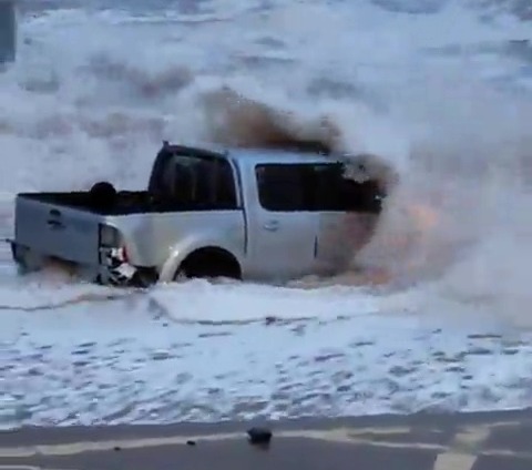 An abandoned 4×4 is battered by waves in Devon