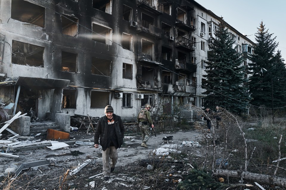 A resident walks with a soldier through rubble in Avdiivka