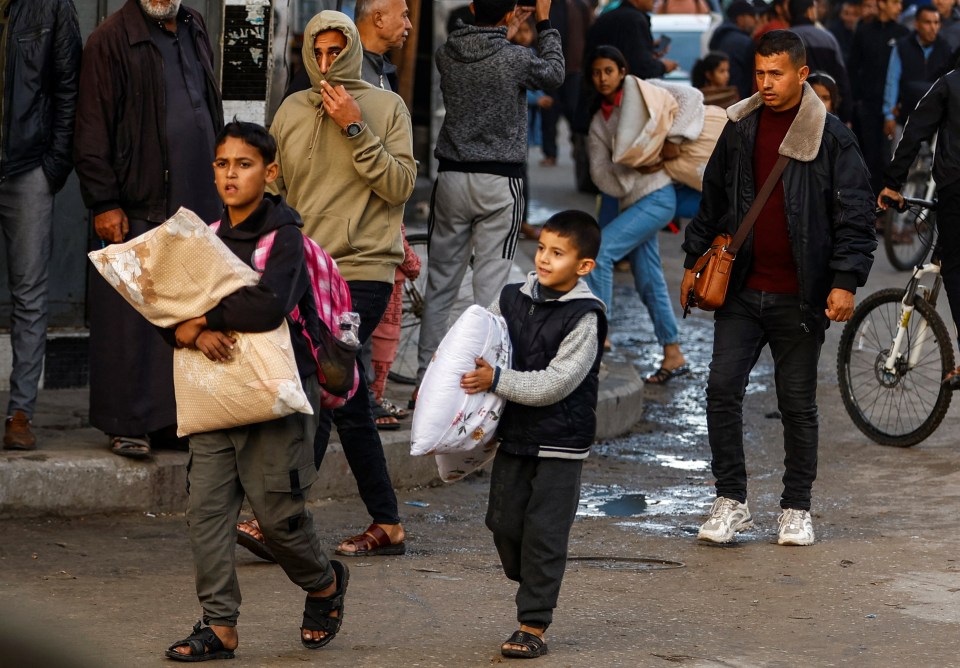 Palestinian children carry belongings as they look to make their way home