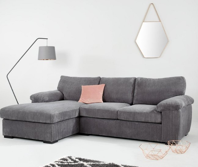 Grey corduroy corner sofa with pink cushion.