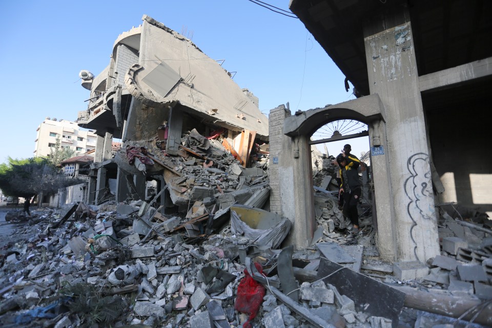 Palestinians walk by buildings destroyed in the Israeli bombardment of the Gaza Strip in Rafah