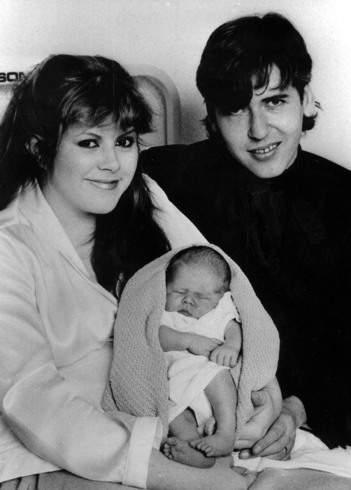 a black and white photo of a man and woman holding a baby