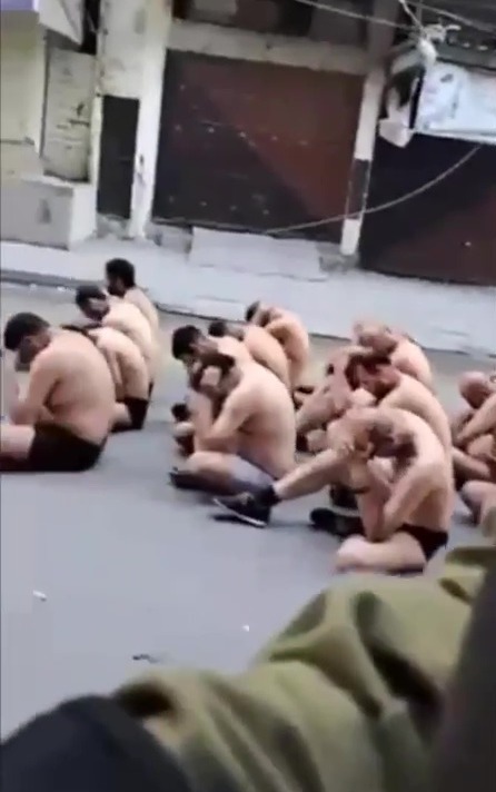 The men were made to sit in the street half naked as others were taken away in trucks