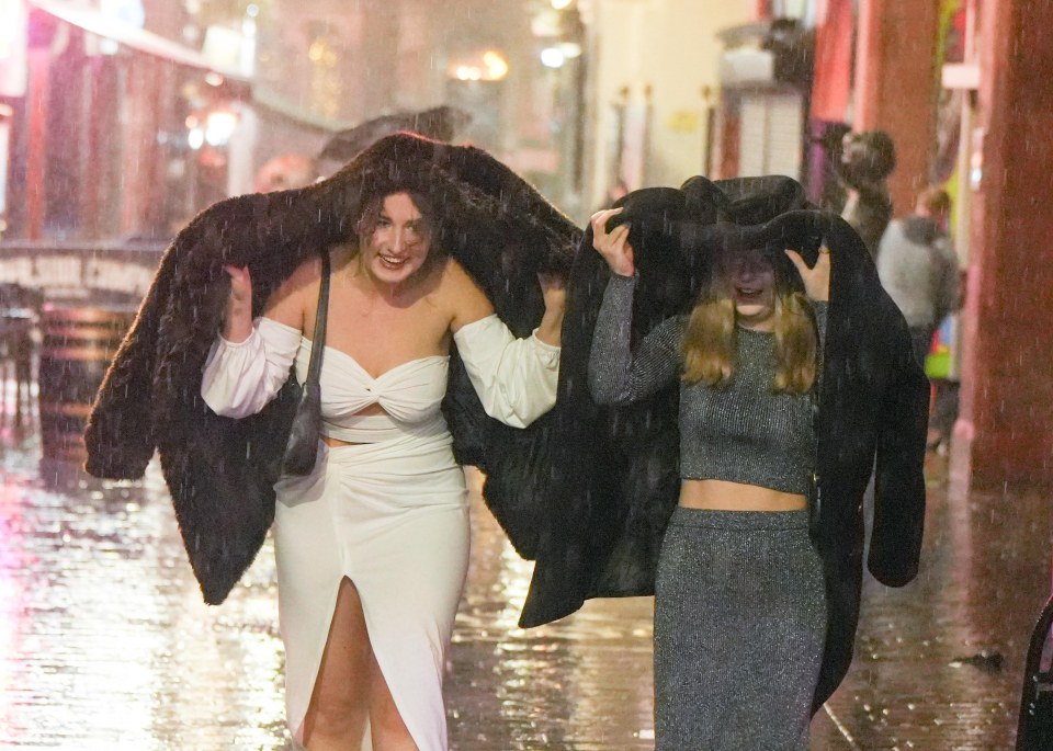 Partygoers in Liverpool used their coats for shelter as the rain pelted down