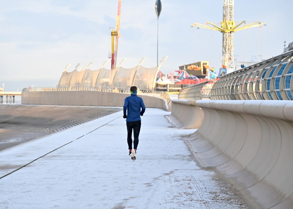 A hardy runner dashes through the snow on the Blackpool coastline