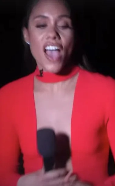 a woman in a red dress is sticking her tongue out in front of a microphone .