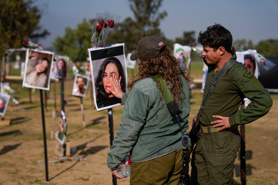 Israeli soldiers look at photos of people killed and taken captive by Hamas militants during their attack on the Supernova desert rave on October 7