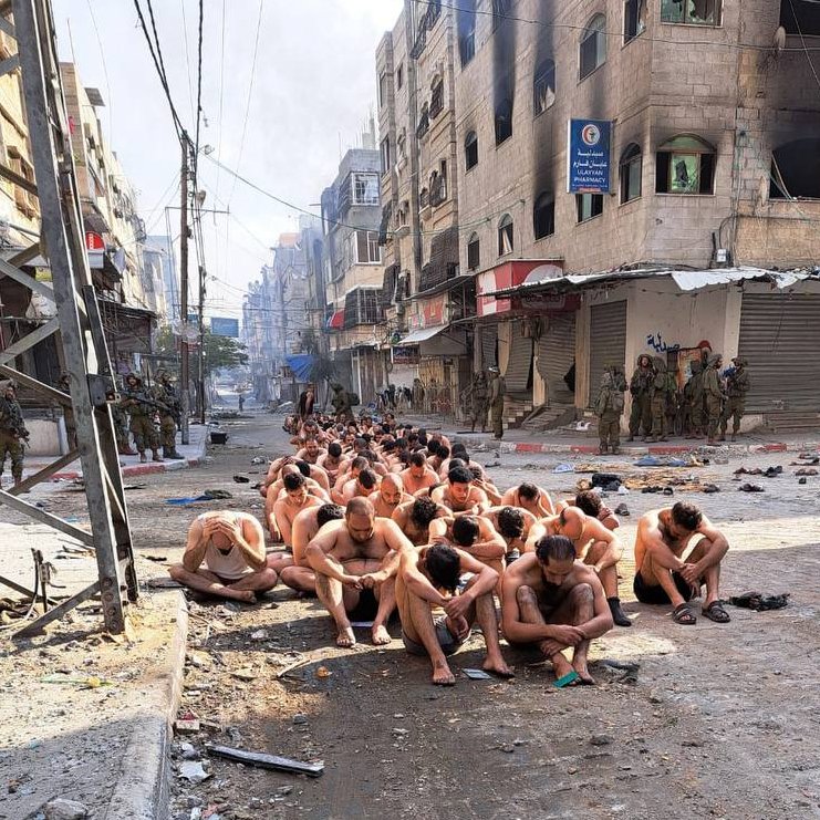 The suspects sit in a line after being arrested by the IDF