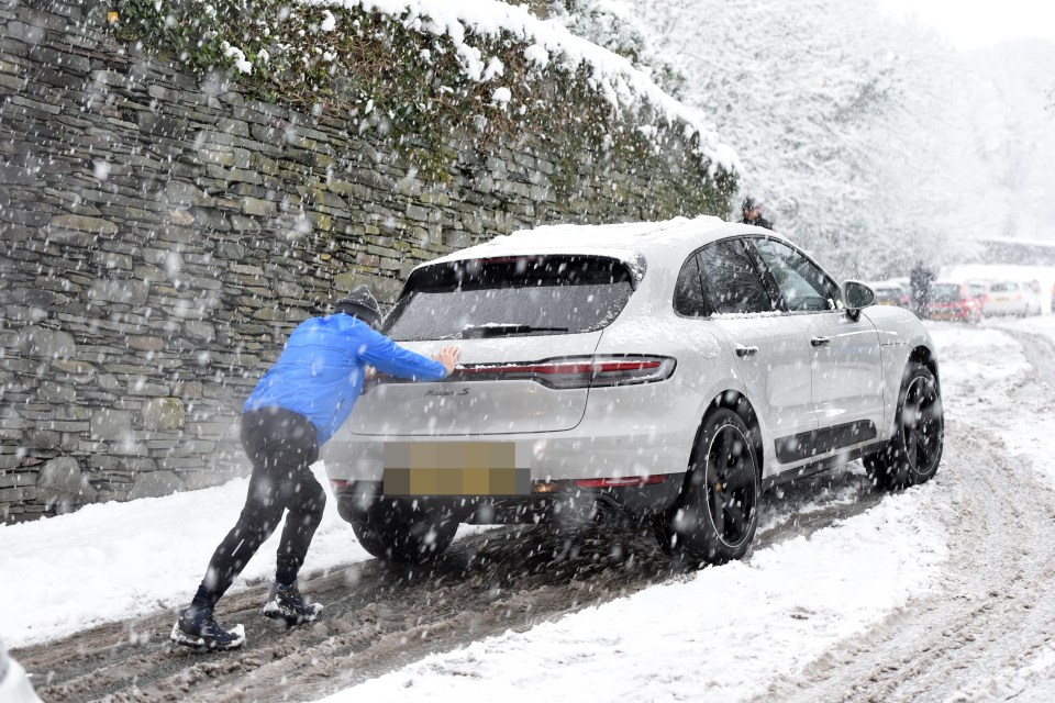 A man pushes a car in Windermere in Cumbria where a major incident was declared