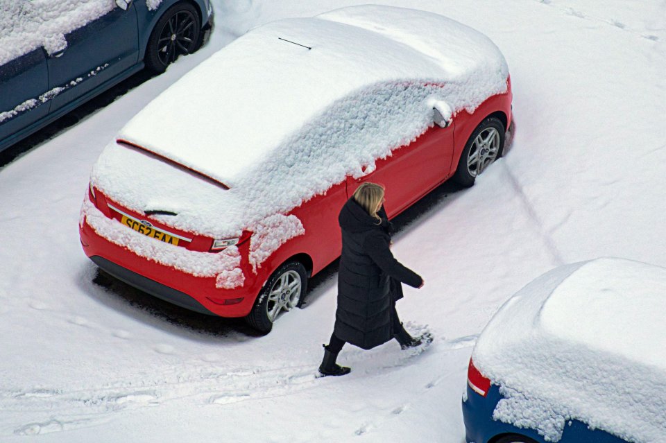 A woman wrapped up in a warm coat trudges through a blanket of snow in Glasgow