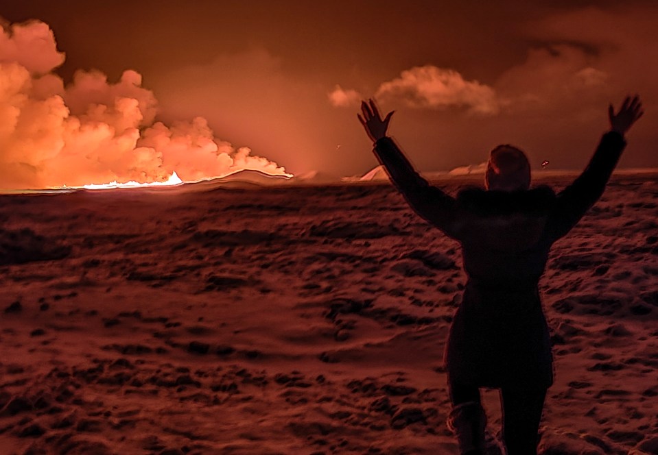 A local resident watches as the night sky turns orange from the volcanic eruption on the Reykjanes peninsula