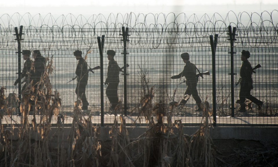 North Korean soldiers patrol next to the border fence across from the Chinese border