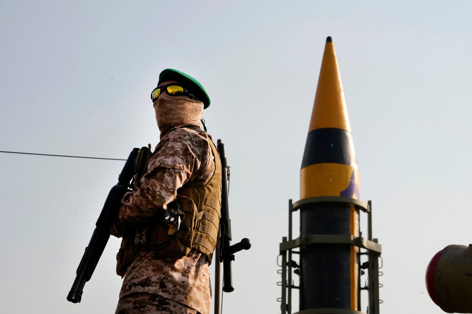 An Iranian Revolutionary Guardsman stands next to a missile