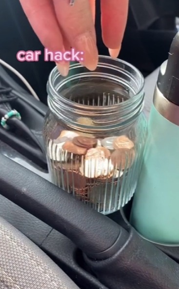 She fills a clear jar with loose change from the central console