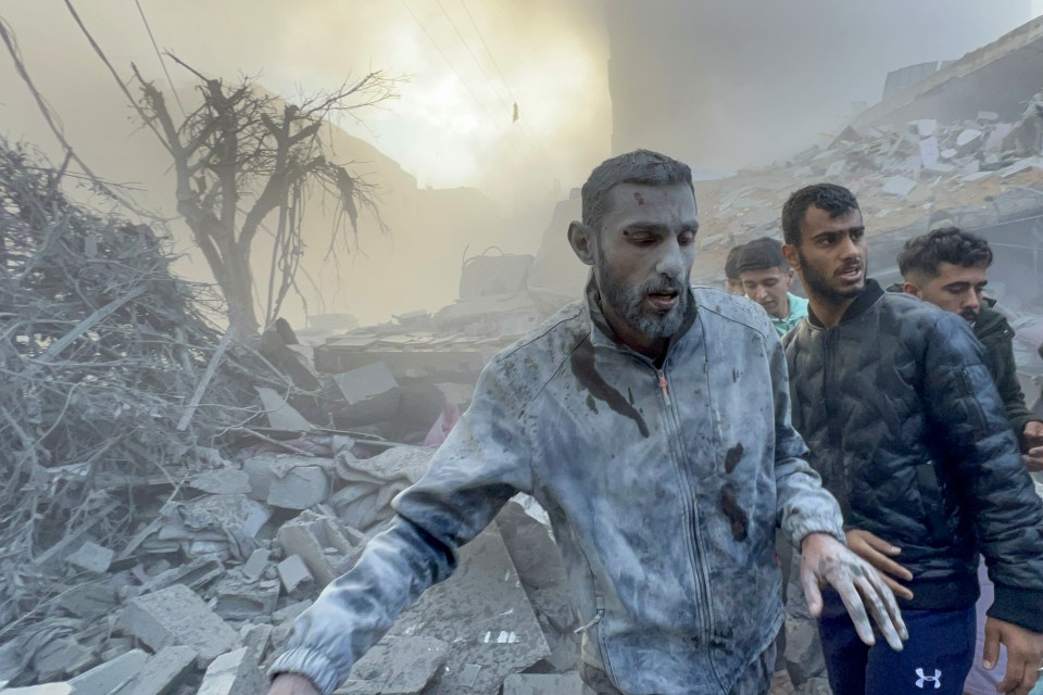 Survivors walk among the rubble of a building hit in yesterday’s strikes