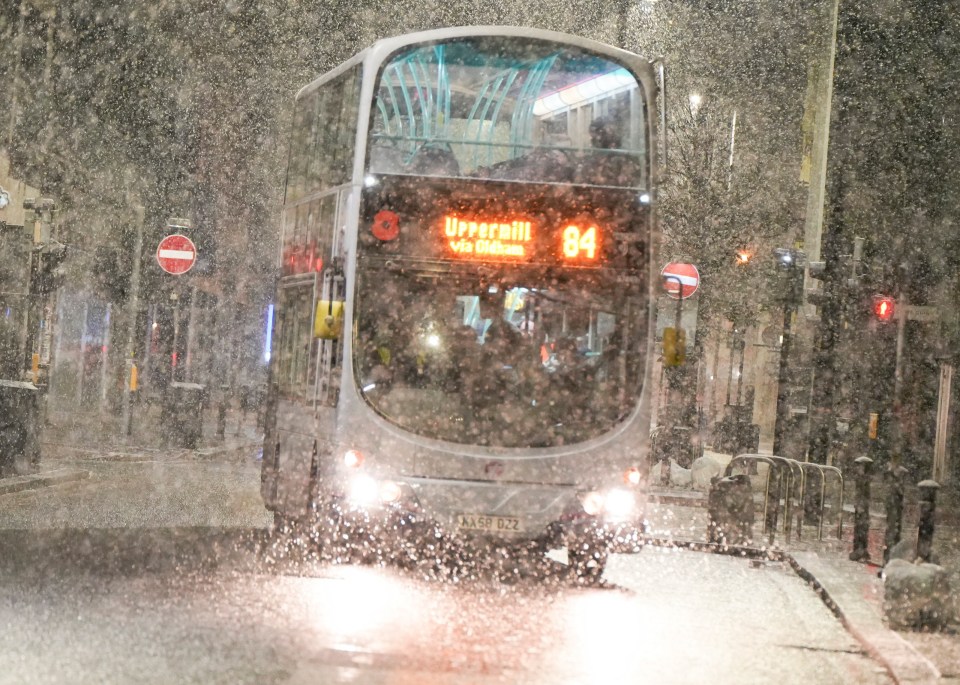 A bus driving through heavy snow in Manchester this morning