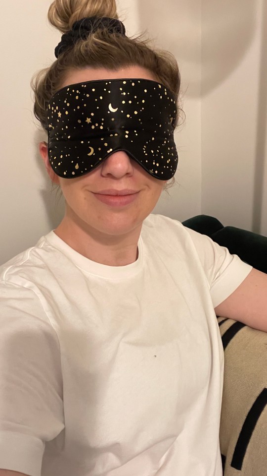 Woman wearing a black sleep mask with gold stars and moons.