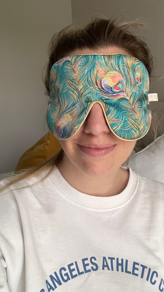 Person wearing a peacock-patterned sleep mask.