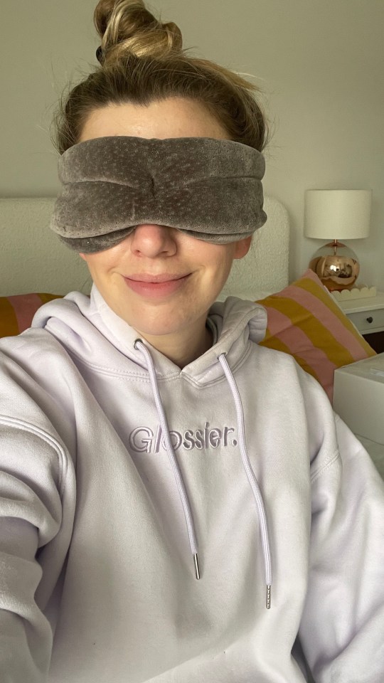 Woman wearing a sleep mask and Glossier hoodie.