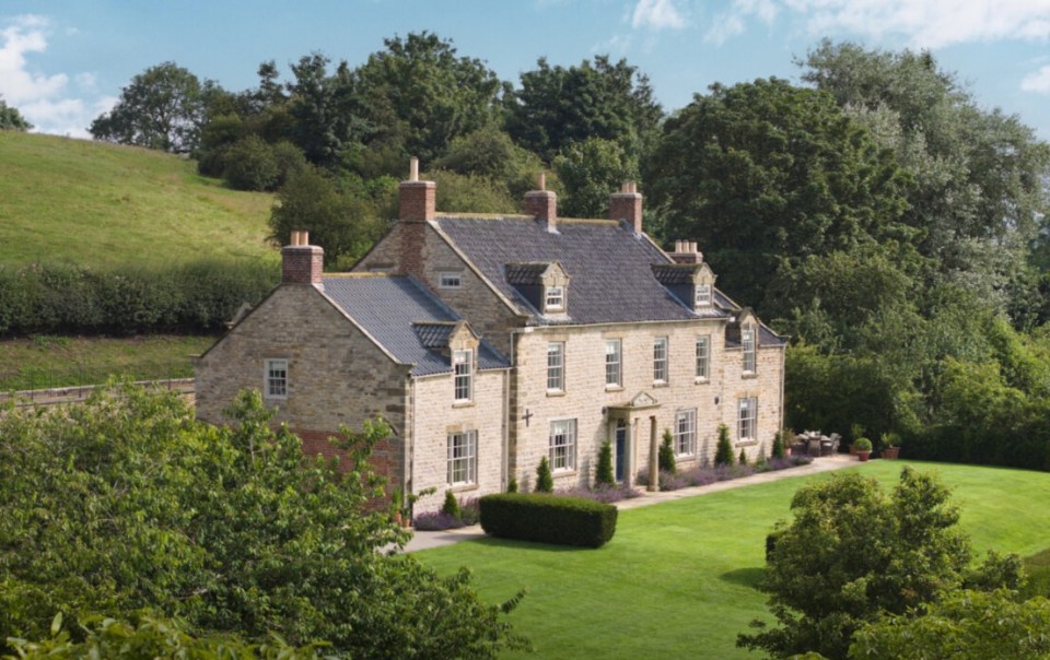 a large house sits in the middle of a lush green field