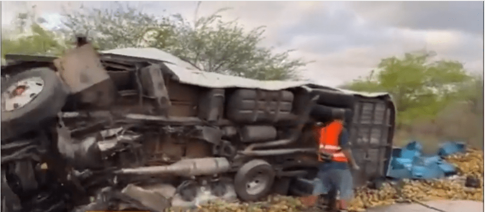 Daylight footage of the aftermath showing the upturned bus surrounded by mangoes spilled from the truck it collided with