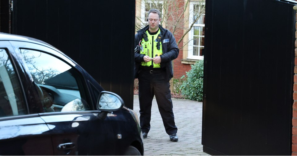 A cop stands guard at the gates of the mansion this morning