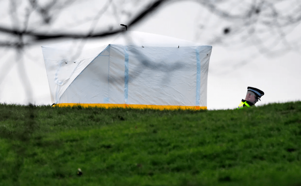 A police officer stands next to a police tent at the scene on Primrose Hill