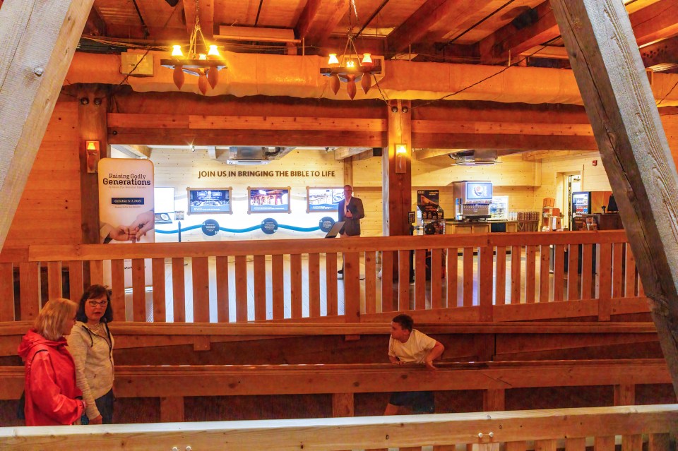 People walk around the ark near signs on the wall about the Bible