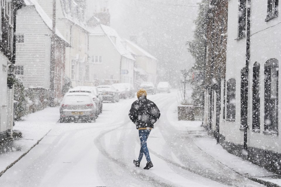 A person walking through a snow flurry in Lenham, Kent