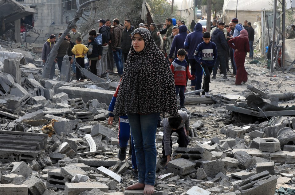 A barefoot Palestinian girl walks through rubble in Rafah following an Israeli strike