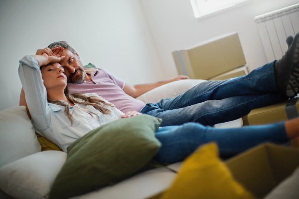 Married couple moving in a new apartment. They are sitting on the sofa, tired.