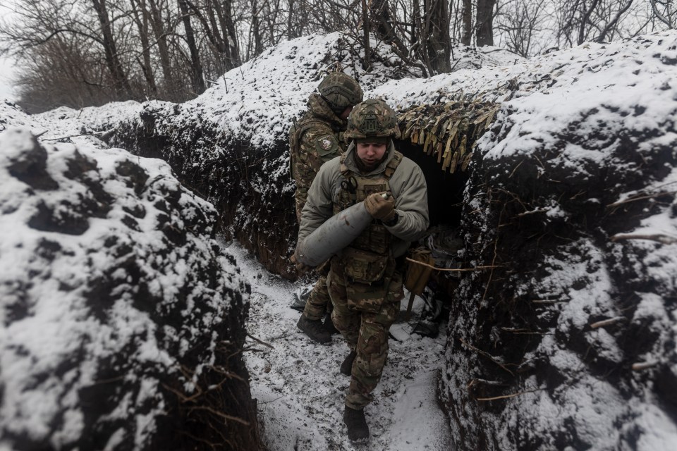 A Ukrainian soldier in the 'Tsunami' regiment carries an artillery shell through a snow-covered trench