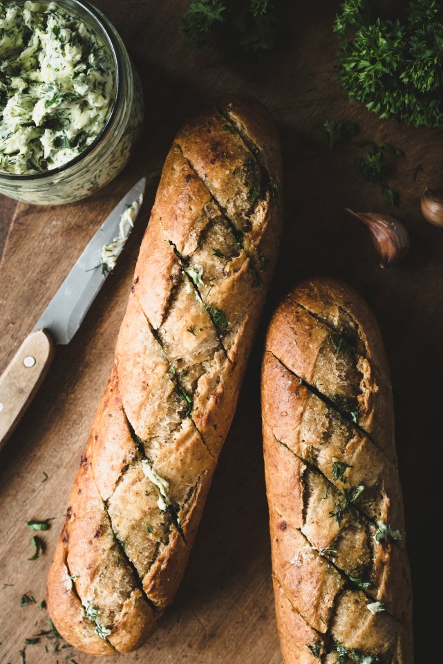 Garlic butter baked baguette. Compound butter with herbs and garlic. Rustic food composition