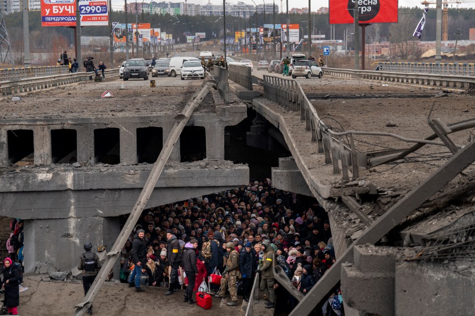 Ukrainians crowd under a destroyed bridge as they try to flee Ukraine capital Kyiv over the Irpin river, March 2022