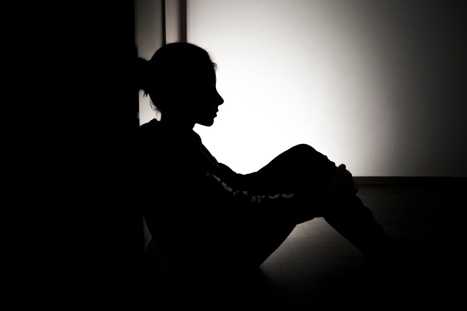 Silhouette of a girl sitting alone in a dark room.