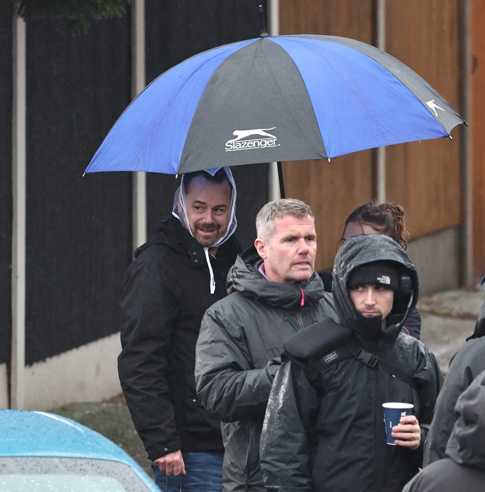 Production crew made sure he had an extra layer of covering from the rain with the umbrella