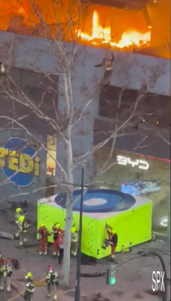 A firefighter leaps from the building onto a mat deployed by emergency services